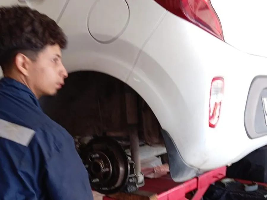 Mecánico cambiando frenos de un auto en el elevador