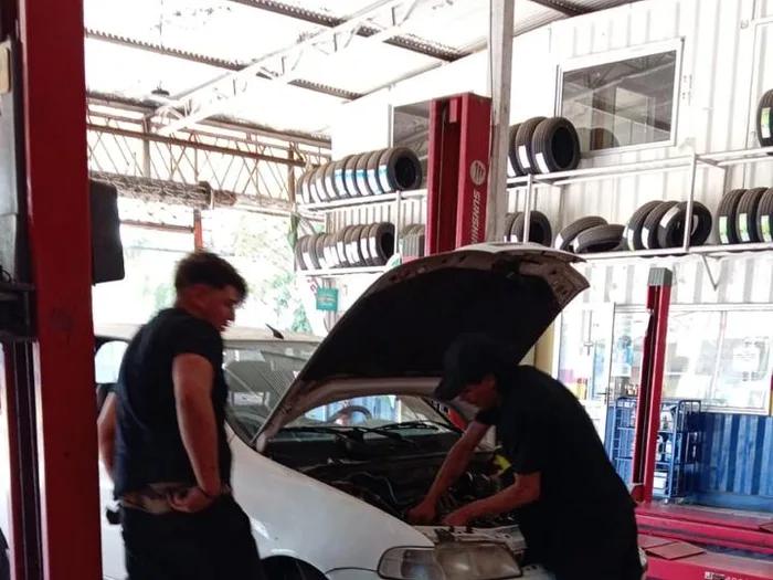 Dos mecánicos revisando el motor de un auto